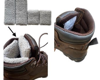 Peut inclure: Une paire de bottes de travail en cuir marron avec un col rembourré et un insert en polaire gris amovible. L'insert est placé à l'intérieur de l'ouverture de la botte, avec des coussinets en polaire gris supplémentaires affichés au-dessus.