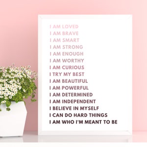 May include: A white framed print with a pink background and black text that reads "I am loved, I am brave, I am smart, I am strong, I am enough, I am worthy, I am curious, I try my best, I am beautiful, I am powerful, I am determined, I am independent, I believe in myself, I can do hard things, I am who I'm meant to be."