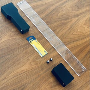 Puede incluir: Un conjunto de herramientas para trabajar la madera que incluye una manija de plástico negro, una regla de plástico transparente con una escala de 3/4, un pequeño paquete amarillo de hojas de sierra Irwin 685 y dos perillas de plástico negro.