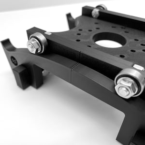 Puede incluir: Una plataforma negra impresa en 3D con cuatro ruedas y un agujero central. La plataforma est&aacute; dise&ntilde;ada para ser utilizada con una impresora 3D.
