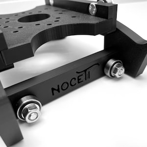 Puede incluir: Un deslizador de c&aacute;mara negro impreso en 3D con la palabra "NOCETI" grabada en el lateral. El deslizador tiene dos rodamientos met&aacute;licos y un tornillo met&aacute;lico a cada lado.