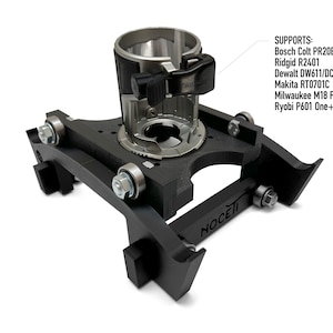 Puede incluir: Base de mesa de enrutador negra con un enrutador plateado montado en la parte superior. La base tiene la palabra "NOCETI" impresa en ella. El enrutador est&aacute; etiquetado con el texto "SUPPORTS: Bosch Colt PR20EVS Ridgid R2401 Dewalt DW611/DCW600 Makita RT0701C Milwaukee M18 Fuel Ryobi P601 One+"