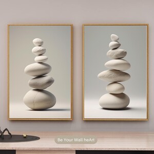Puede incluir: Dos impresiones enmarcadas de una pila de piedras blancas, cada impresi&oacute;n tiene una disposici&oacute;n diferente de piedras, las impresiones est&aacute;n en una pared blanca con un estante de madera debajo.