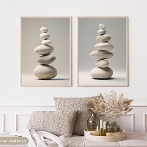 Puede incluir: Dos impresiones de arte de pared minimalistas que presentan piedras blancas apiladas en una disposici&oacute;n zen. Las impresiones est&aacute;n enmarcadas en un marco de madera claro y tienen un fondo blanco.