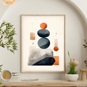 May include: Abstract geometric wall art print featuring a stack of blue and gray stones with orange circles on a beige background. The print is framed and hanging on a white wall.