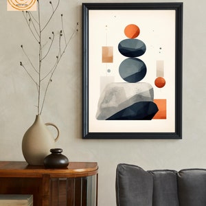 May include: Abstract geometric art print with a white background, featuring stacked blue and gray circles, orange and red squares and rectangles, and a gray and white rock-like shape at the bottom. The print is framed in black.