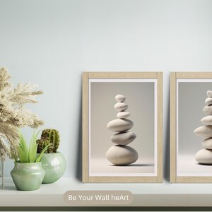 Puede incluir: Dos impresiones enmarcadas de piedras apiladas en un estilo minimalista. Las impresiones est&aacute;n en marcos de madera y tienen un fondo gris claro.