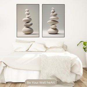Puede incluir: Dos impresiones enmarcadas de piedras blancas apiladas sobre un fondo gris. Las impresiones est&aacute;n colgadas en una pared blanca sobre una cama blanca con una manta blanca y dos almohadas blancas. Hay una l&aacute;mpara azul en el lado izquierdo de la imagen y una planta verde en una maceta blanca en el lado derecho de la imagen. El texto "Be Your Wall heArt" est&aacute; en la parte inferior de la imagen.