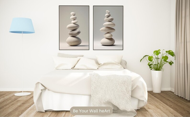 Puede incluir: Dos impresiones enmarcadas de piedras blancas apiladas sobre un fondo gris. Las impresiones est&aacute;n colgadas en una pared blanca sobre una cama blanca con una manta blanca y dos almohadas blancas. Hay una l&aacute;mpara azul en el lado izquierdo de la imagen y una planta verde en una maceta blanca en el lado derecho de la imagen. El texto "Be Your Wall heArt" est&aacute; en la parte inferior de la imagen.
