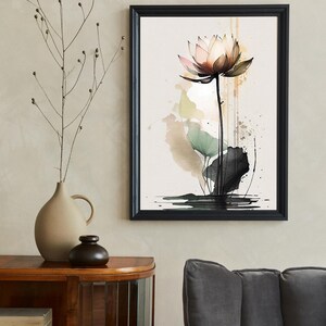 May include: A watercolor painting of a pink lotus flower with green leaves and black ink splatters on a beige background. The painting is framed in a black frame.