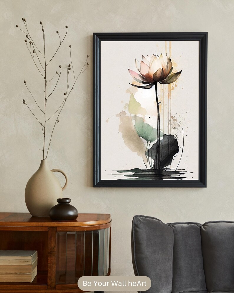 May include: A watercolor painting of a pink lotus flower with green leaves and black ink splatters on a beige background. The painting is framed in a black frame.