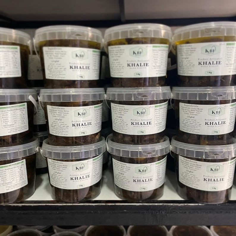 May include: A shelf stocked with multiple clear plastic containers filled with a dark brown liquid. Each container has a white label with the text "KBF KHALIE" printed on it.