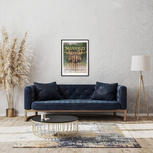 May include: A framed poster with a black background and a gold title that reads "Manderley". The poster features a photograph of a large, imposing house seen through a wrought iron gate. The text below the title reads "Daphne du Maurier classic".