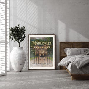 May include: A framed print of a vintage poster with a gold and black design. The poster features a large, ornate gate with a stone building behind it. The text on the poster reads "Visit Manderley, Dream of Coming Again & Again".
