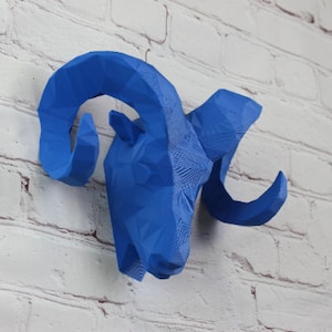 May include: A blue geometric ram head sculpture with large horns. The sculpture is made of a 3D printed material and has a textured surface.