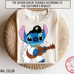 May include: A white t-shirt with a blue cartoon character playing a guitar. The character is wearing a white suit and has a blue mohawk. The text "CANVAS" is visible on the shirt.