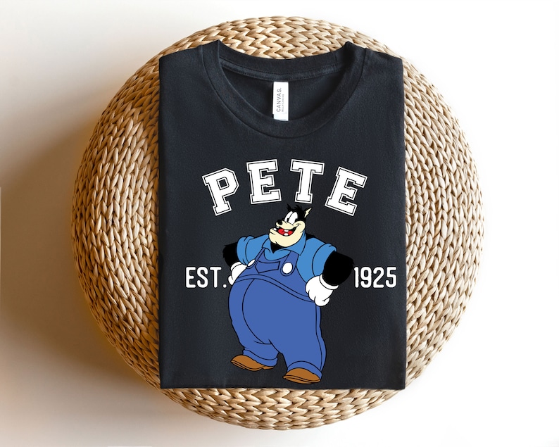 Puede incluir: Camiseta negra con una imagen de dibujos animados de Pete el cachorro con un mono y el texto "PETE EST. 1925".