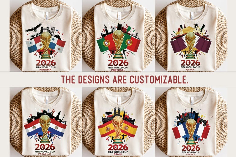May include: Cream-coloured t-shirts displaying FIFA World Cup 2026 designs. Each shirt showcases a gold trophy, flags, and cityscapes representing Panama, Portugal, Qatar, Paraguay, Spain, and France. The text "2026 FIFA World Cup" is visible on each shirt.