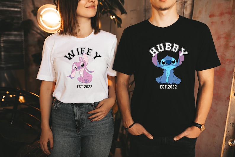 May include: A couple wearing matching t-shirts featuring a cartoon Stitch character. The woman's shirt reads "Wifey Est. 2022" and the man's shirt reads "Hubby Est. 2022".