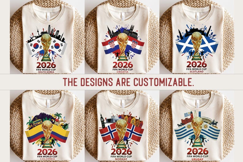 May include: A collection of cream-coloured t-shirts, each showcasing a FIFA World Cup 2026 design. The shirts display a golden trophy, flags, and cityscapes representing South Korea, Croatia, Scotland, Colombia, Norway, and Uruguay. Text reads "2026 FIFA World Cup". The text "THE DESIGNS ARE CUSTOMIZABLE" is also present.