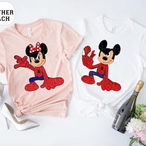 May include: Two t-shirts, one pale pink and one white, each with a cartoon character in a Spider-Man-themed outfit. The pale pink shirt features Minnie Mouse, and the white shirt features Mickey Mouse. The text "HEATHER PEACH" is in a white oval.
