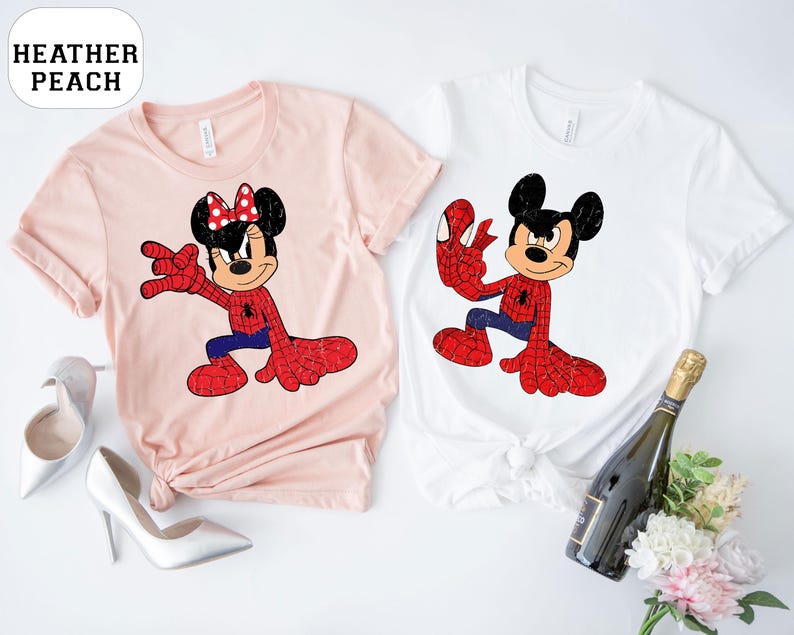 May include: Two t-shirts, one pale pink and one white, each with a cartoon character in a Spider-Man-themed outfit. The pale pink shirt features Minnie Mouse, and the white shirt features Mickey Mouse. The text "HEATHER PEACH" is in a white oval.