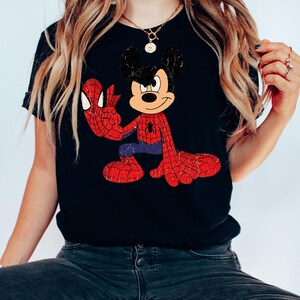 May include: Black t-shirt with a distressed graphic of Mickey Mouse as Spider-Man. The design shows Mickey in a red and blue Spider-Man suit with webbed arms and legs. The shirt has a classic, vintage style.
