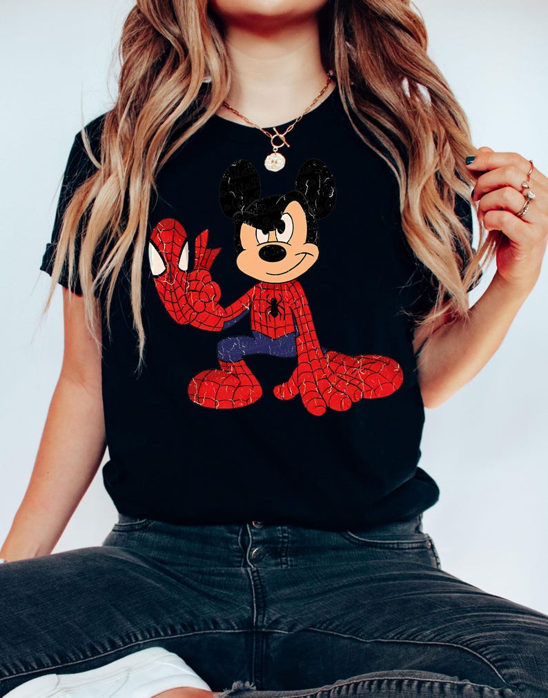 May include: Black t-shirt with a distressed graphic of Mickey Mouse as Spider-Man. The design shows Mickey in a red and blue Spider-Man suit with webbed arms and legs. The shirt has a classic, vintage style.