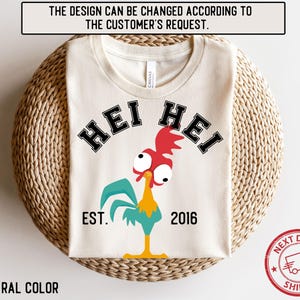 Könnte beinhalten: Ein weißes T-Shirt mit einer Hühnerillustration und dem Text "Hei Hei Est. 2016".