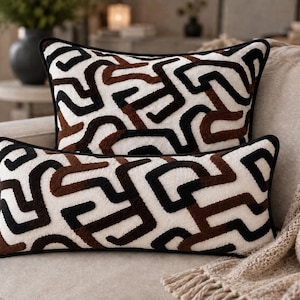 May include: Two rectangular throw pillows featuring a textured, cream-colored base with a bold, raised geometric pattern in black and dark brown. Each pillow is finished with a thin black piped edge, creating a cohesive and structured appearance.