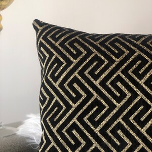 May include: Black and gold decorative pillow with a geometric pattern.