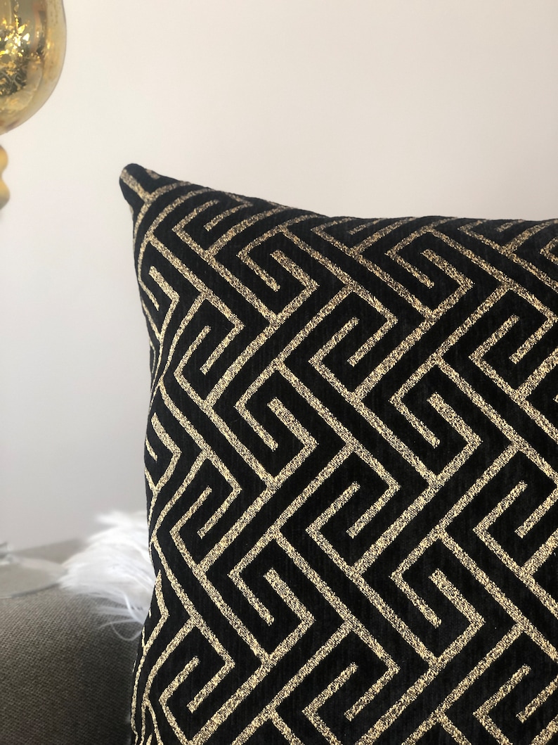 May include: Black and gold decorative pillow with a geometric pattern.