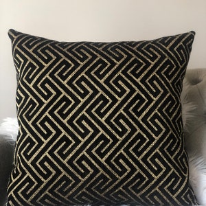 May include: Black and gold decorative throw pillow with a geometric pattern.