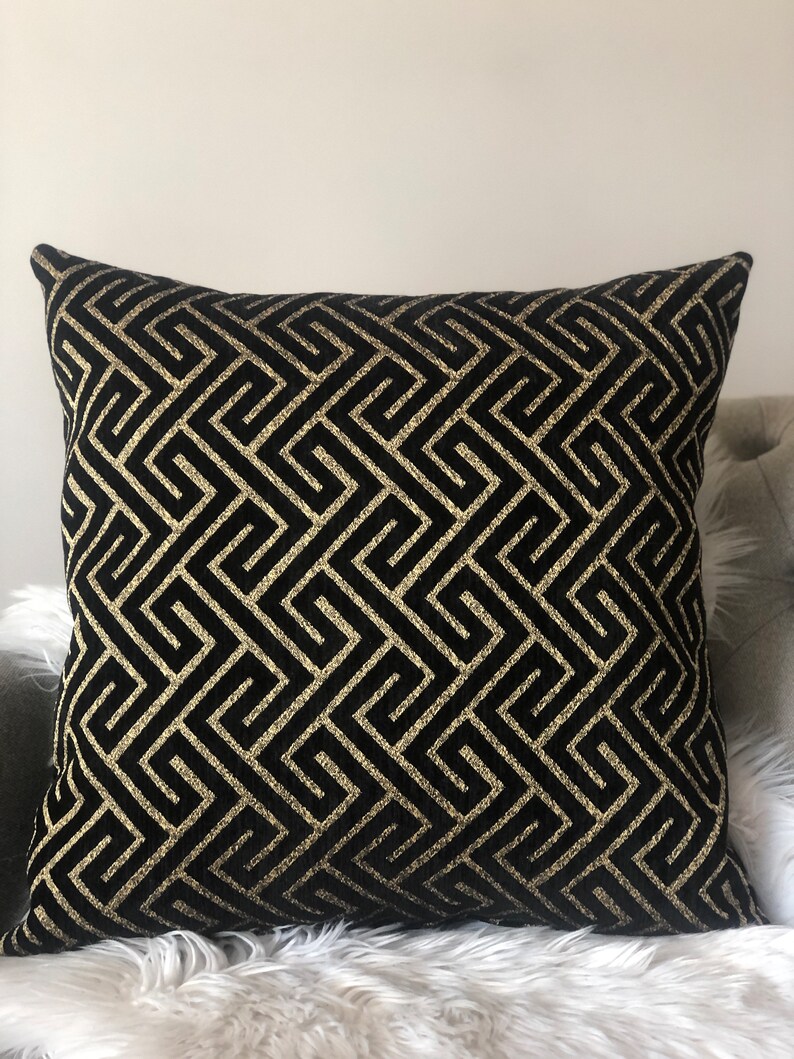 May include: Black and gold decorative throw pillow with a geometric pattern.