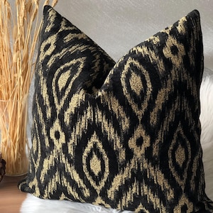 Può includere: Cuscino decorativo nero e oro con motivo ikat.