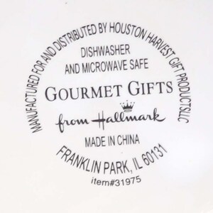 May include: A white ceramic plate with black text that reads "Manufactured for and distributed by Houston Harvest Gift Products LLC. Dishwasher and microwave safe. Gourmet Gifts from Hallmark. Made in China. Franklin Park, IL 60131. Item #31975."