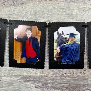 Puede incluir: Un banner de fotos de graduación con cuatro marcos negros. Cada marco tiene una foto diferente de un joven con toga y birrete de graduación, traje y ropa informal. El banner es perfecto para una fiesta de graduación.