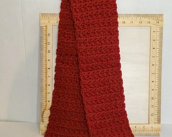 May include: A red crocheted scarf hanging on a black hanger. The scarf is approximately 12 inches long.