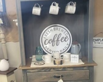 May include: A gray wooden hutch with a cabinet and drawers below. The hutch has shelves and a sign that says "Fresh Brewed Coffee Served Daily".