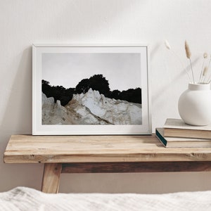Peut inclure: Une impression encadr&eacute;e blanche d'une photographie de paysage repr&eacute;sentant une falaise rocheuse blanche avec une for&ecirc;t vert fonc&eacute; en arri&egrave;re-plan.
