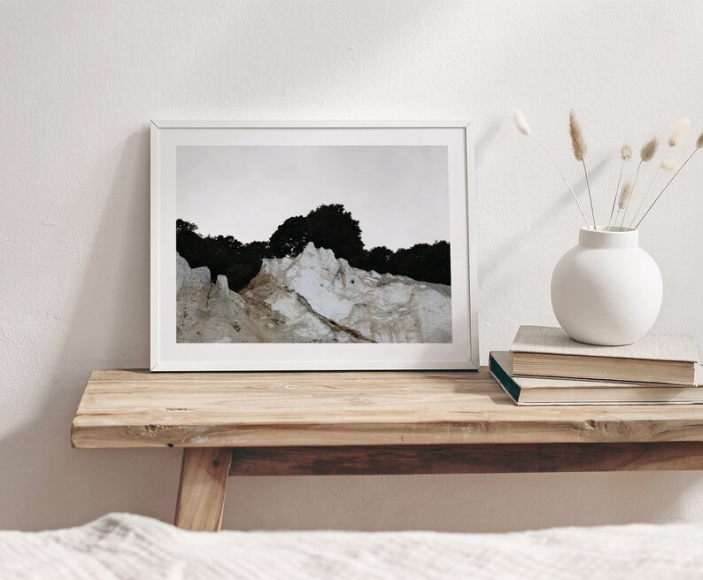 Peut inclure: Une impression encadr&eacute;e blanche d'une photographie de paysage repr&eacute;sentant une falaise rocheuse blanche avec une for&ecirc;t vert fonc&eacute; en arri&egrave;re-plan.