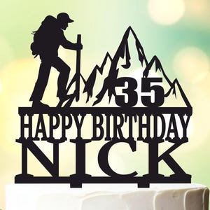 May include: Black silhouette cake topper featuring a hiker climbing a mountain with the text "Happy Birthday Nick" and the number "35" on the mountain.