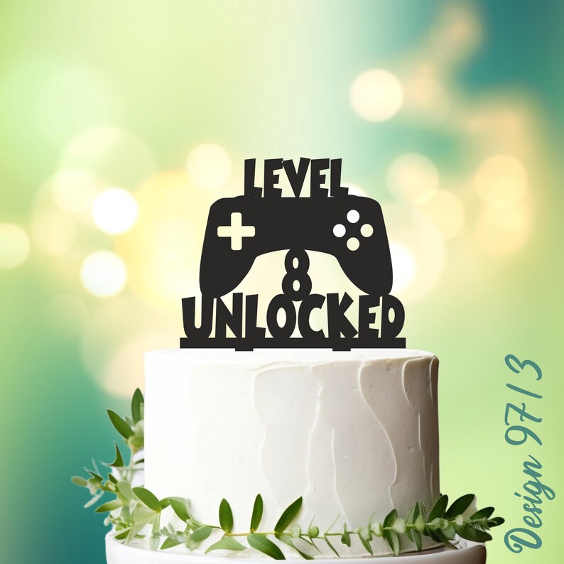 May include: Black cake topper with a video game controller and the text "Level 8 Unlocked".