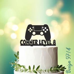 May include: Black and white cake topper featuring a video game controller and the text "Conner Level 8".