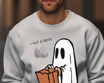 Puede incluir: Sudadera gris claro con el texto "I GOT A ROCK" encima de un fantasma de dibujos animados sosteniendo una bolsa de papel marrón. El fantasma tiene ojos ovalados negros y un cuerpo blanco. Un gráfico de roca gris está a la izquierda.
