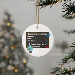 May include: A white ceramic ornament with a chalkboard design. The chalkboard has the phrases "Believe in yourselves," "Dream," "Try," and "Do good." It also says "I love you all." A paper airplane and globe are also featured.