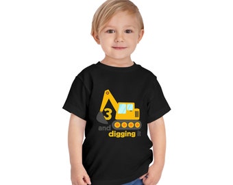 Könnte beinhalten: Schwarzes Kleinkind-T-Shirt mit gelber Bagger-Grafik. Der Bagger hat die Zahl 3 und die Worte "and digging it" darunter gedruckt. Das Shirt wird von einem kleinen Kind getragen.