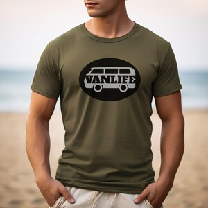 A man in a military green t-shirt with a black embellishment featuring a graphic of a van that reads VAN LIFE