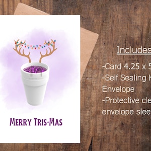 May include: A white paper cup with purple glitter inside and a pair of brown reindeer antlers with colorful string lights on top. The text "Merry Tris-Mas" is written below the cup.