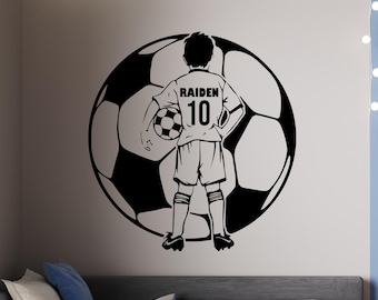 May include: Black and white wall decal of a soccer player standing in front of a soccer ball. The player is wearing a jersey with the name "Raiden" and the number "10" on it.